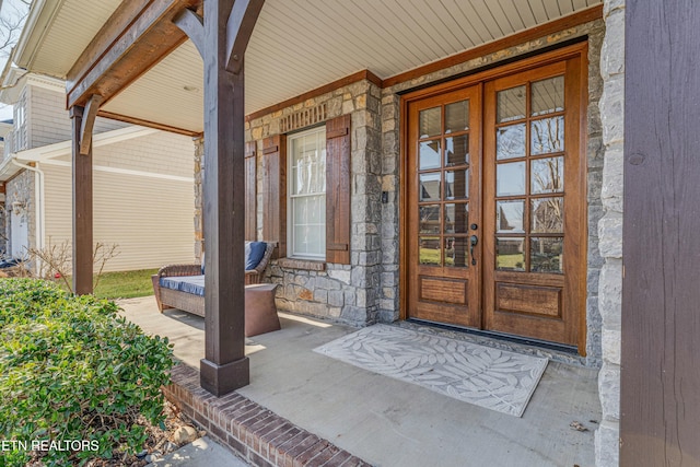 doorway to property with a porch and stone siding