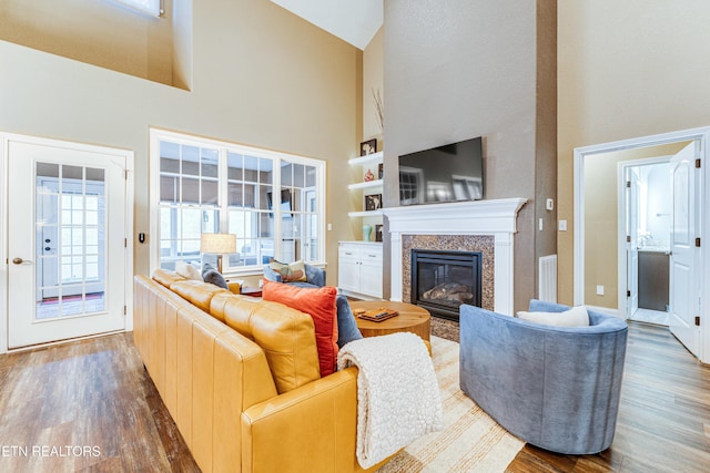 living area featuring visible vents, a high ceiling, wood finished floors, and a high end fireplace