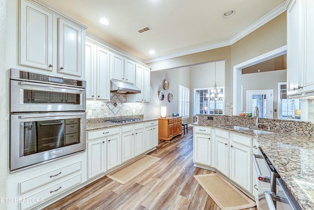 kitchen featuring stainless steel appliances, visible vents, white cabinetry, light stone countertops, and under cabinet range hood