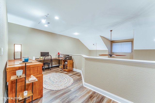 home office featuring lofted ceiling, rail lighting, a ceiling fan, wood finished floors, and baseboards