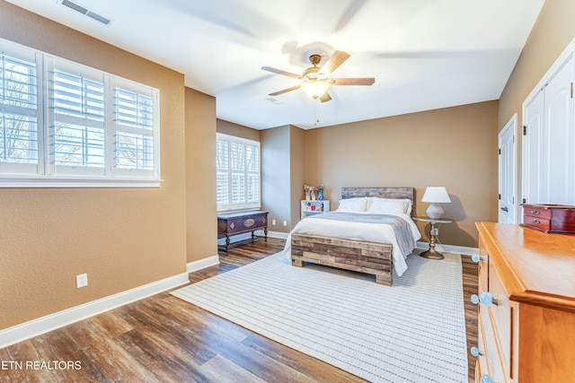 bedroom with a ceiling fan, dark wood finished floors, visible vents, and baseboards