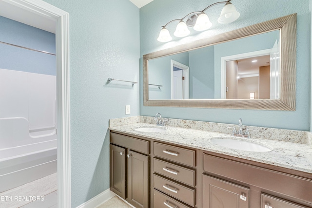 bathroom with double vanity, a sink, and baseboards