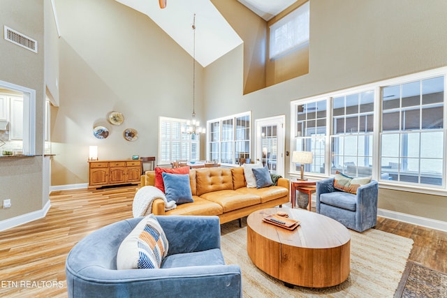 living area featuring baseboards, wood finished floors, visible vents, and an inviting chandelier