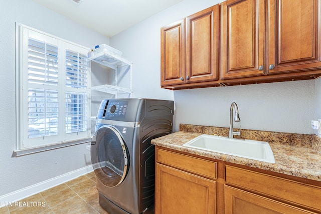 laundry area with light tile patterned flooring, a sink, baseboards, cabinet space, and washer / clothes dryer