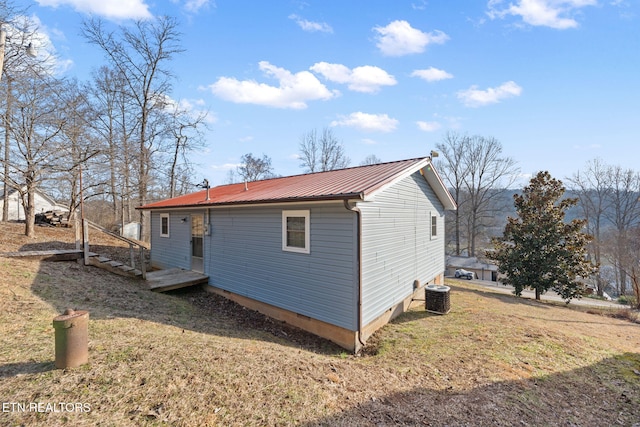 view of property exterior with central AC unit and a yard