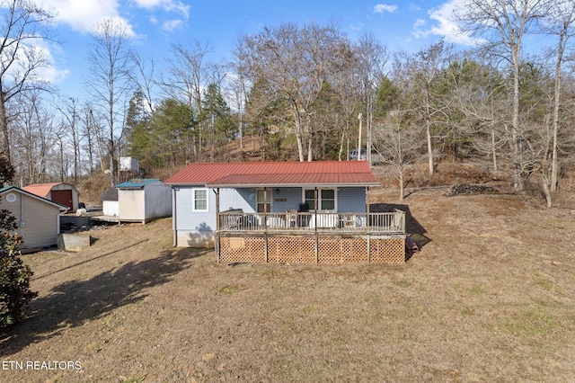 rear view of property with a wooden deck, covered porch, a shed, and a lawn