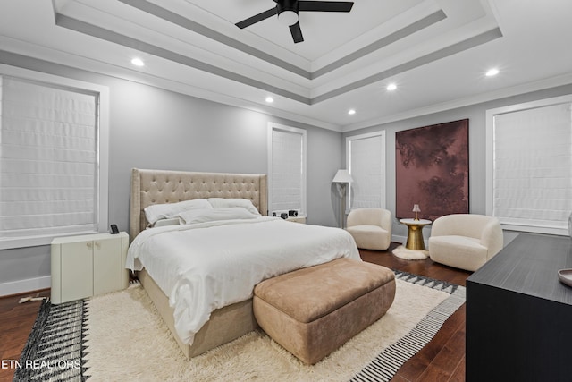 bedroom featuring ornamental molding, a raised ceiling, dark wood-type flooring, and recessed lighting