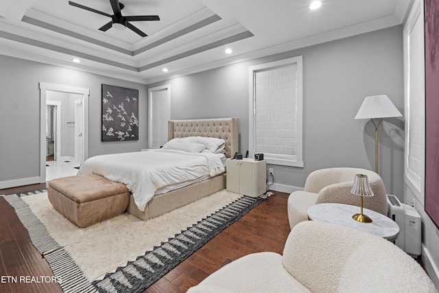 bedroom with recessed lighting, wood finished floors, baseboards, ornamental molding, and a raised ceiling