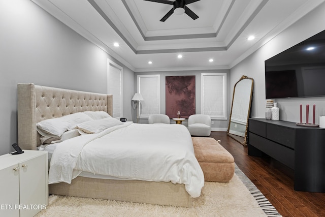 bedroom with dark wood finished floors, a raised ceiling, ceiling fan, ornamental molding, and recessed lighting