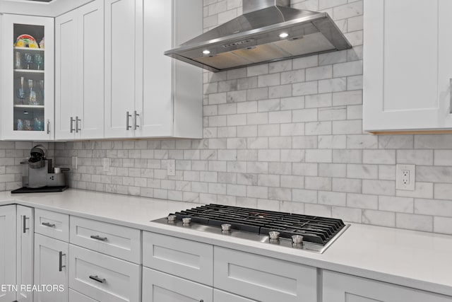 kitchen featuring tasteful backsplash, white cabinets, wall chimney exhaust hood, light countertops, and stainless steel gas cooktop