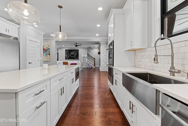 kitchen featuring light countertops, decorative backsplash, appliances with stainless steel finishes, open floor plan, and a sink