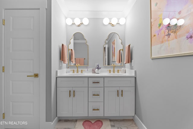 bathroom featuring marble finish floor, a sink, baseboards, and double vanity