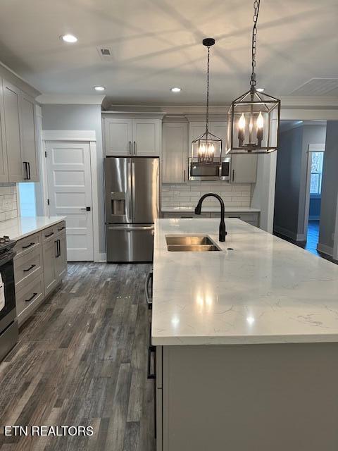 kitchen with dark wood-style floors, light stone counters, stainless steel refrigerator with ice dispenser, gray cabinets, and a sink