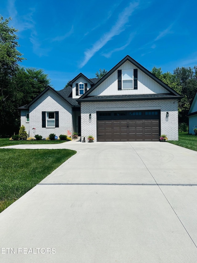 view of front of home with a front lawn, concrete driveway, and brick siding