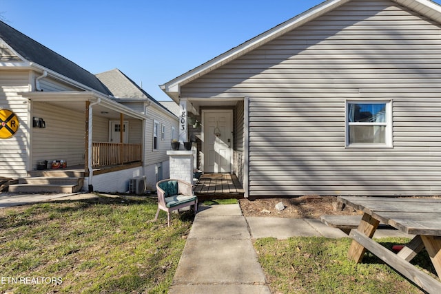 view of front of home with a porch, cooling unit, and a front lawn