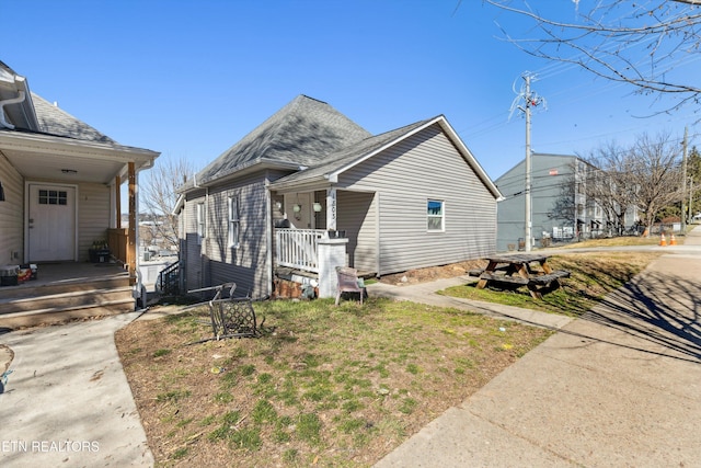 view of side of home with a shingled roof and a porch