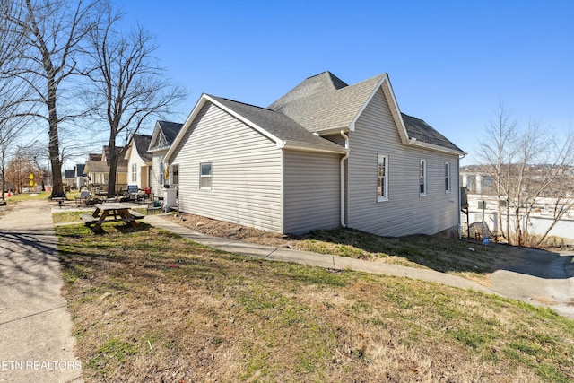 view of property exterior featuring a shingled roof and a lawn