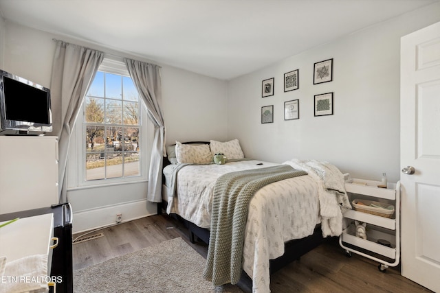 bedroom featuring baseboards, visible vents, and wood finished floors