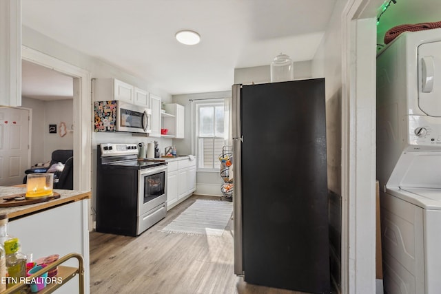 kitchen with stacked washer and dryer, white cabinets, appliances with stainless steel finishes, light wood-type flooring, and open shelves