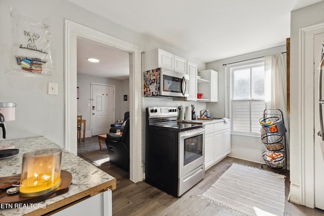 kitchen featuring baseboards, white cabinets, stainless steel appliances, light wood-style floors, and open shelves