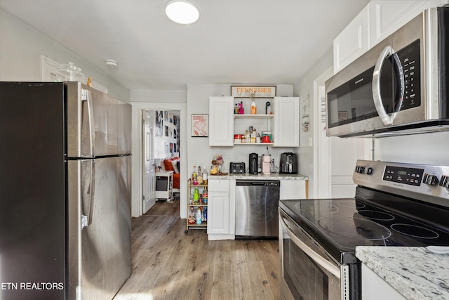 kitchen with light stone counters, open shelves, appliances with stainless steel finishes, white cabinetry, and light wood-type flooring