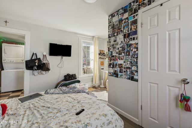 bedroom featuring stacked washing maching and dryer and baseboards