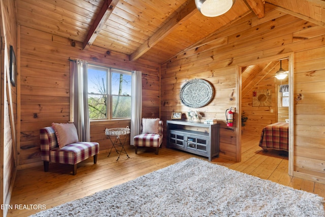 sitting room featuring vaulted ceiling with beams and wooden walls