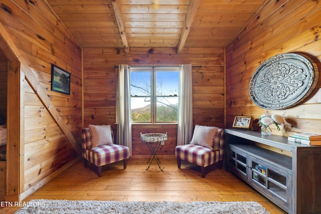 sitting room with lofted ceiling with beams, light wood-type flooring, wood ceiling, and wood walls