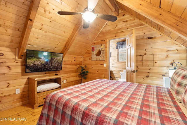 bedroom featuring wood walls, wood ceiling, ensuite bath, lofted ceiling with beams, and light hardwood / wood-style floors