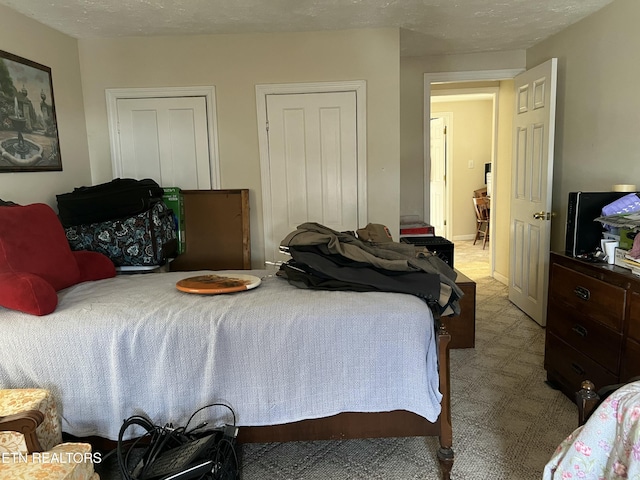 bedroom featuring light colored carpet and a textured ceiling