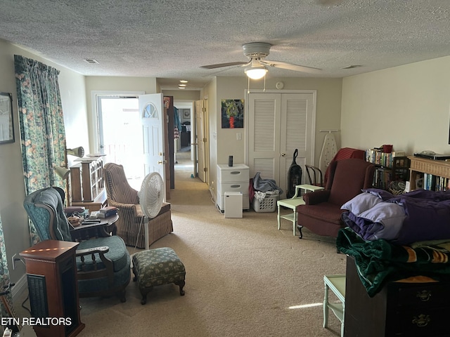 sitting room with light carpet, ceiling fan, and a textured ceiling