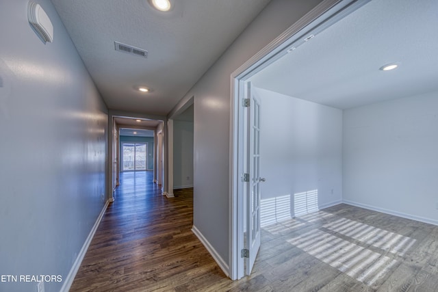 corridor featuring baseboards, visible vents, wood finished floors, a textured ceiling, and recessed lighting