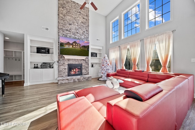 living room with ceiling fan, wood-type flooring, a fireplace, and built in features