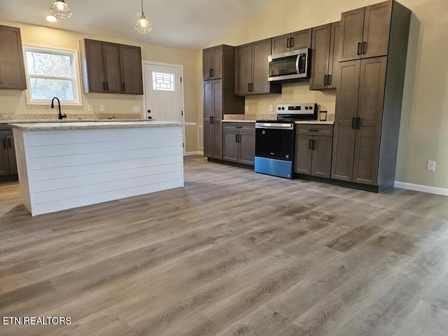 kitchen featuring dark brown cabinets, appliances with stainless steel finishes, hanging light fixtures, and light hardwood / wood-style flooring