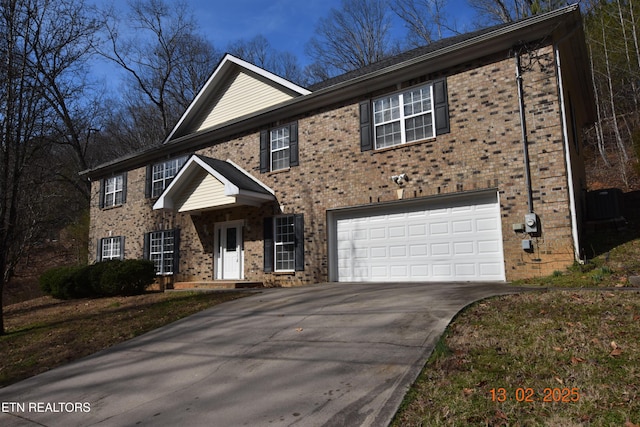 colonial-style house featuring a garage, concrete driveway, and brick siding