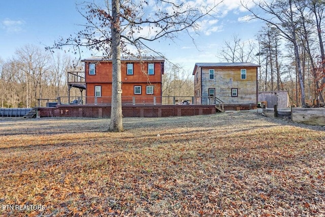 rear view of property with a wooden deck and a lawn