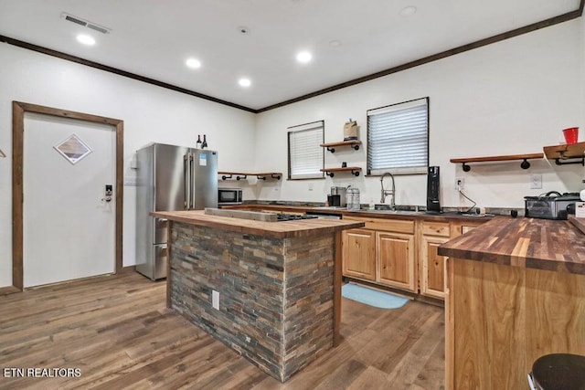 kitchen featuring a center island, sink, butcher block counters, and high end refrigerator