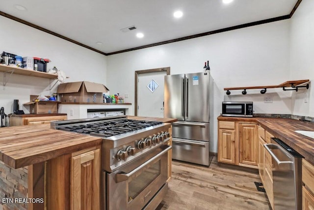 kitchen featuring a kitchen island, butcher block counters, ornamental molding, stainless steel appliances, and light hardwood / wood-style flooring