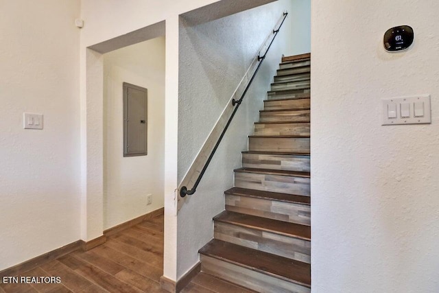 stairway featuring wood-type flooring and electric panel