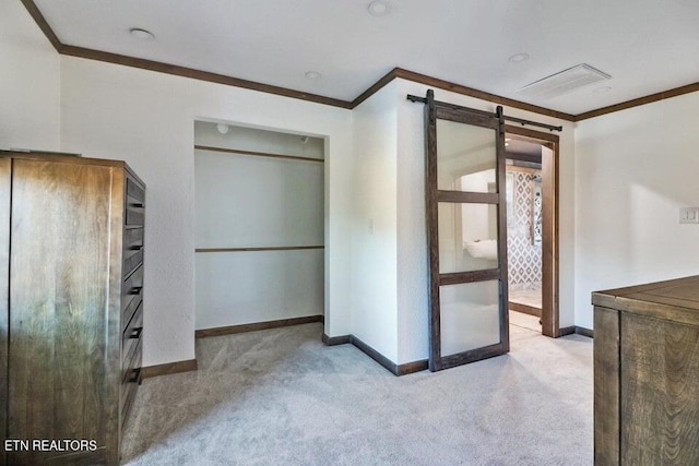 unfurnished bedroom featuring crown molding, light colored carpet, and a barn door