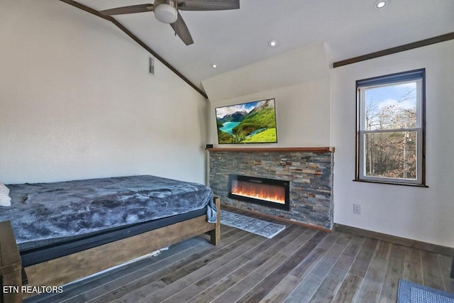 bedroom with ceiling fan, a stone fireplace, vaulted ceiling, and wood-type flooring