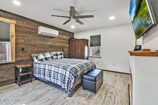 bedroom featuring light hardwood / wood-style flooring, a wall mounted air conditioner, wooden walls, and ceiling fan