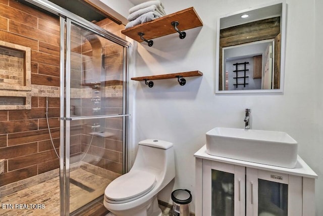 bathroom with vanity, a shower with door, and toilet