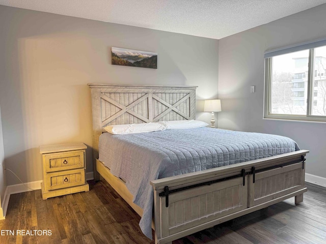 bedroom with dark hardwood / wood-style floors and a textured ceiling