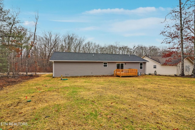 rear view of property with a wooden deck and a lawn