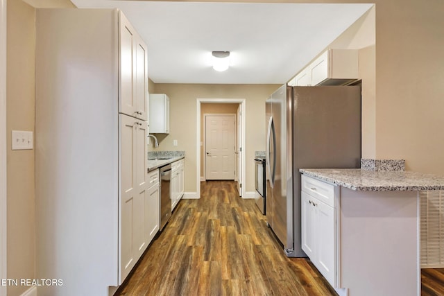 kitchen with appliances with stainless steel finishes, dark hardwood / wood-style floors, white cabinetry, sink, and light stone counters