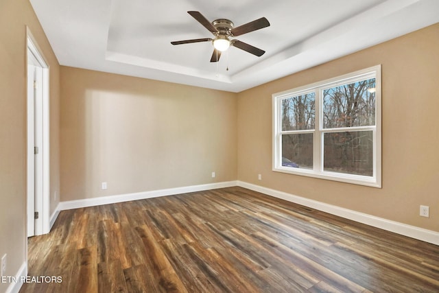 unfurnished room with ceiling fan, dark hardwood / wood-style flooring, and a raised ceiling