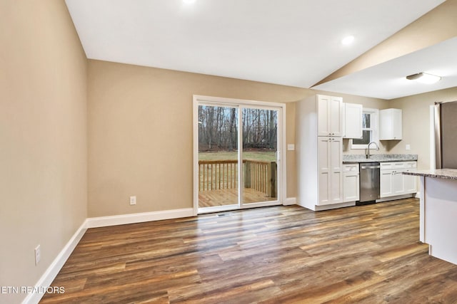 kitchen with lofted ceiling, sink, dark wood-type flooring, white cabinets, and stainless steel dishwasher