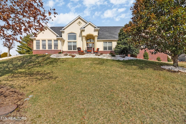 view of front of property featuring stucco siding, a front lawn, and brick siding