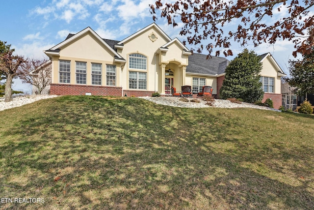 view of front of property featuring stucco siding, a front yard, and brick siding